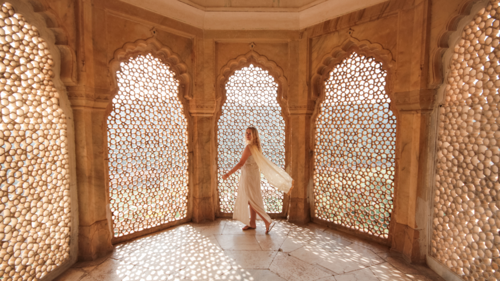Traveller exploring carved stone jali windows during a fort stay in Jaipur