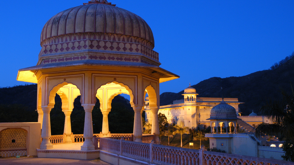 Illuminated heritage fort with domed pavilions near Jaipur at dusk