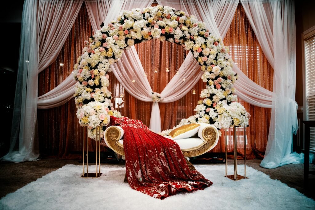 Jaipur Wedding Favours Guests Will Keep 6 This luxurious wedding stage features a large floral arch decorated with white and pink flowers, creating a romantic backdrop for the ceremony.