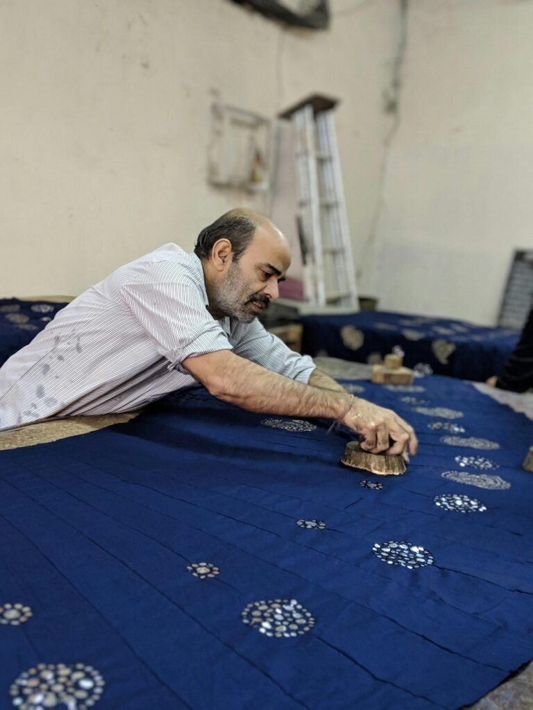 The Guardians of Dwindling Arts: Traditional Craftsmen of Rajasthan 2 Block Printing in Jaipur - A skilled artisan applying traditional block printing techniques on blue fabric in a workshop.