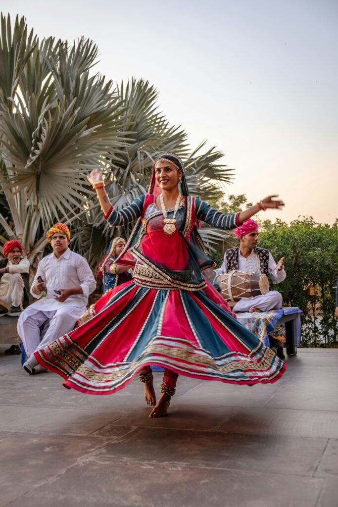 A woman performing a Rajasthani folk dance, likely Ghoomar or Kalbelia, in a colorful traditional ghagra skirt. | Wedding Venue in Jaipur - Dera Mandawa