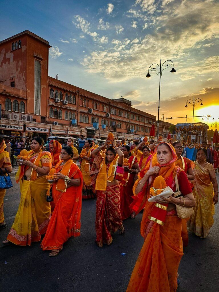 Teej Festival in Jaipur, a Guide to the Pink City's Monsoon Celebration 3 A vibrant procession of women dressed in traditional orange and yellow saris participating in a cultural or religious festival, likely in Jaipur, India | Teej Festival in Jaipur