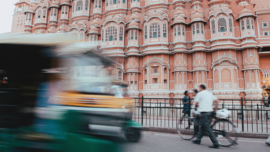 Pink latticed façade of Hawa Mahal with a passing auto-rickshaw, among the easy places to visit in Jaipur with family